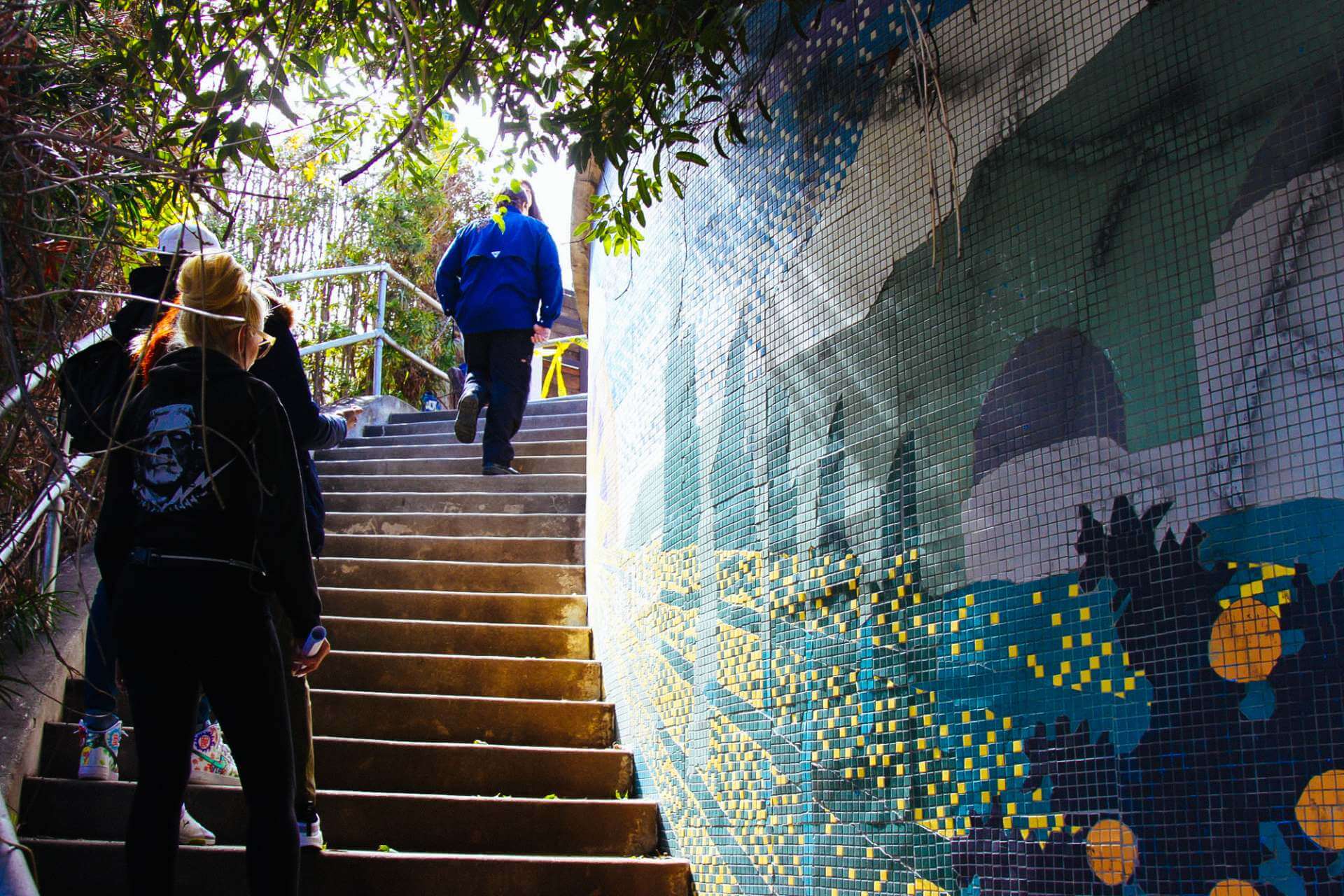 Tour guide walking up steps with mosaic wall