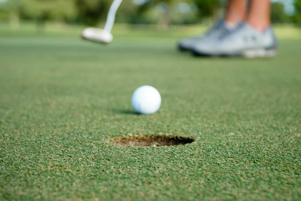 Putter shooting for birdie as golf ball rolls toward the hole on a green during a putt